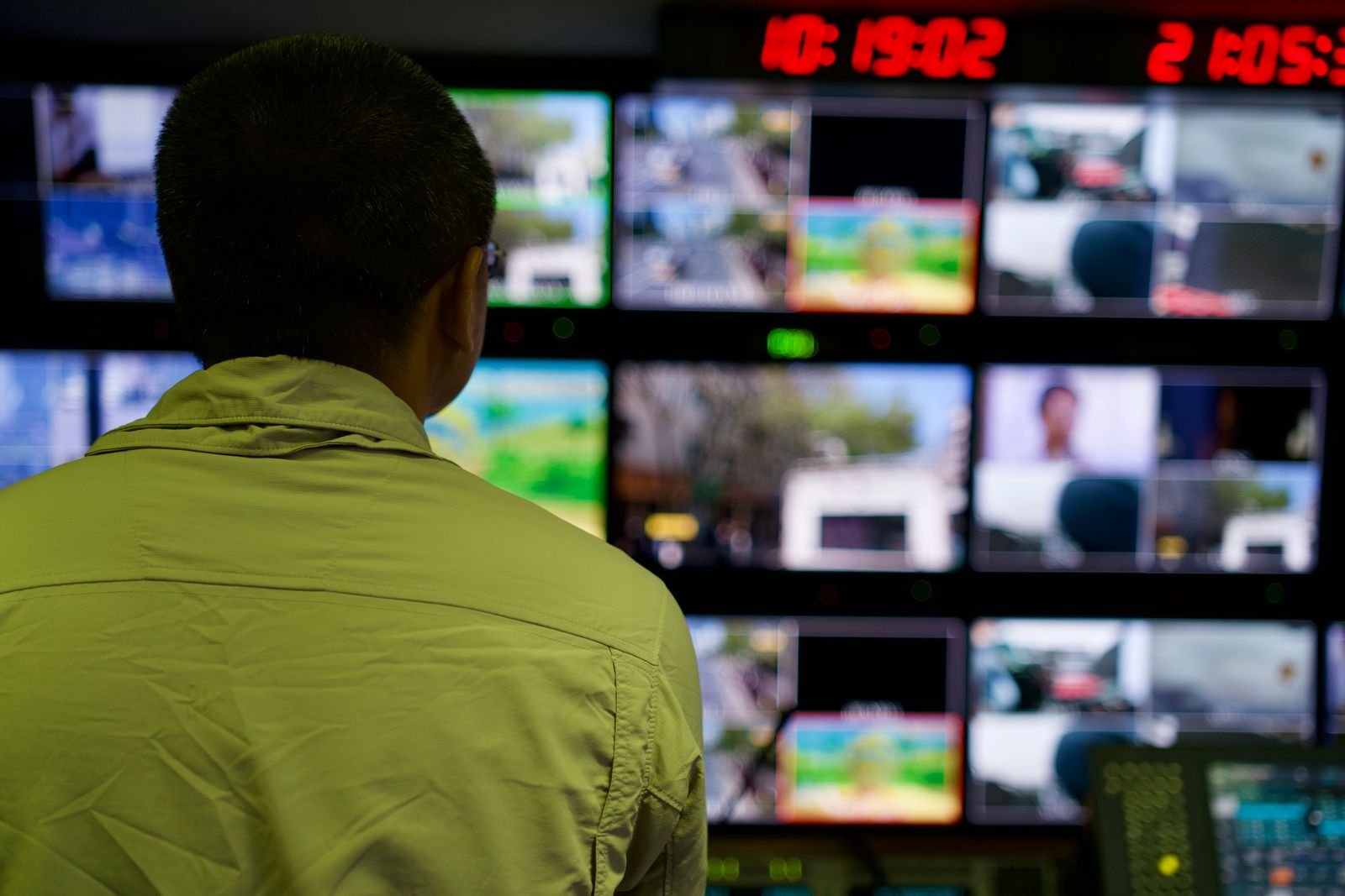 Operator monitoring a wall of connected screens from a central dashboard, representing centralized digital signage management