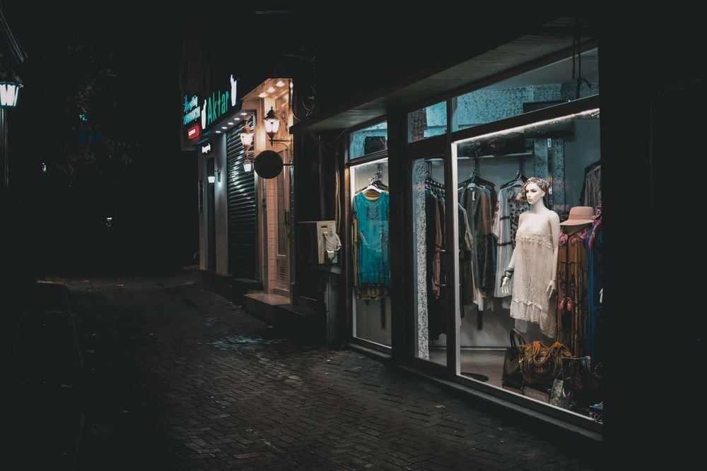 Illuminated retail shop window display at night, advertising products to passersby